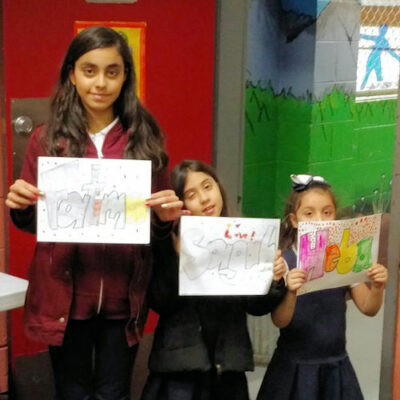 Three girls holding artwork