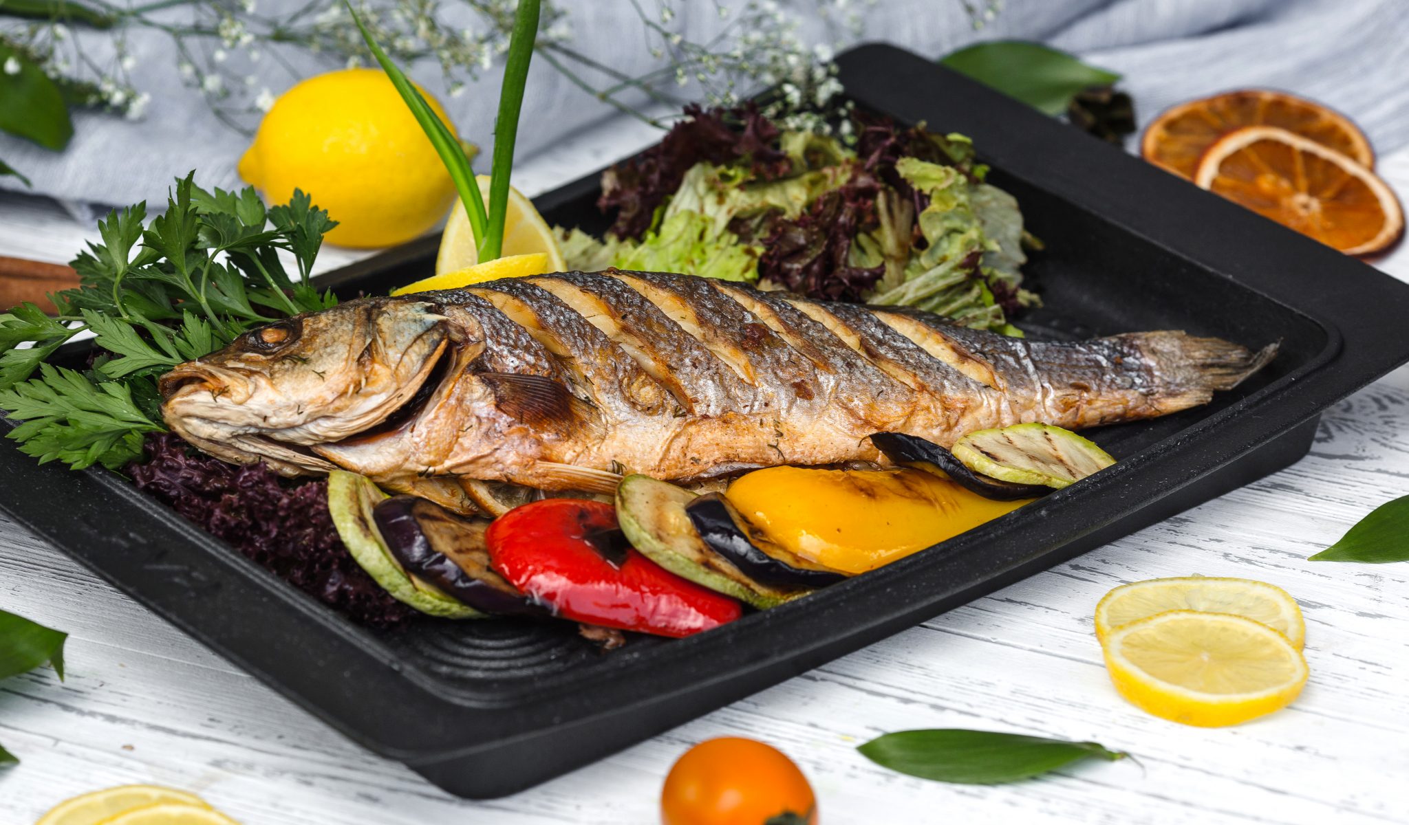 roasted fish garnished with lemon slices served with vegetables | Art ...