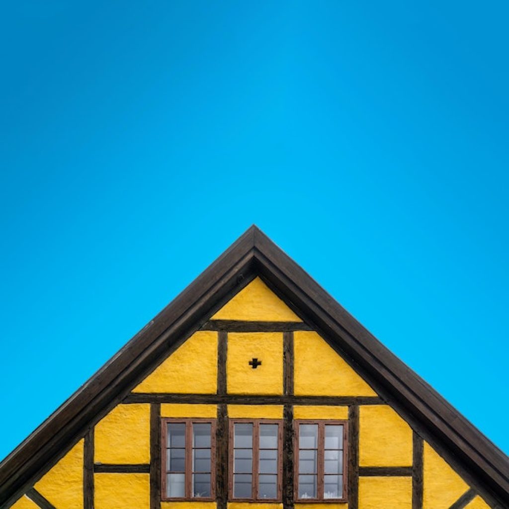 Tip of a yellow home's sharp cornered roof.