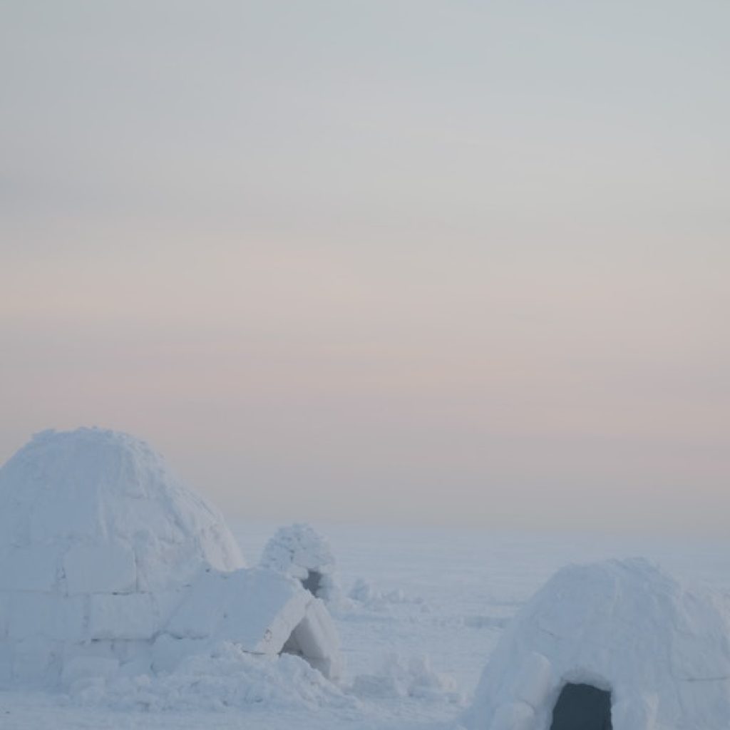 One large igloo next to another small one during a sunset
