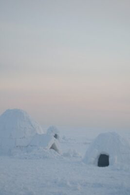 One large igloo next to another small one during a sunset