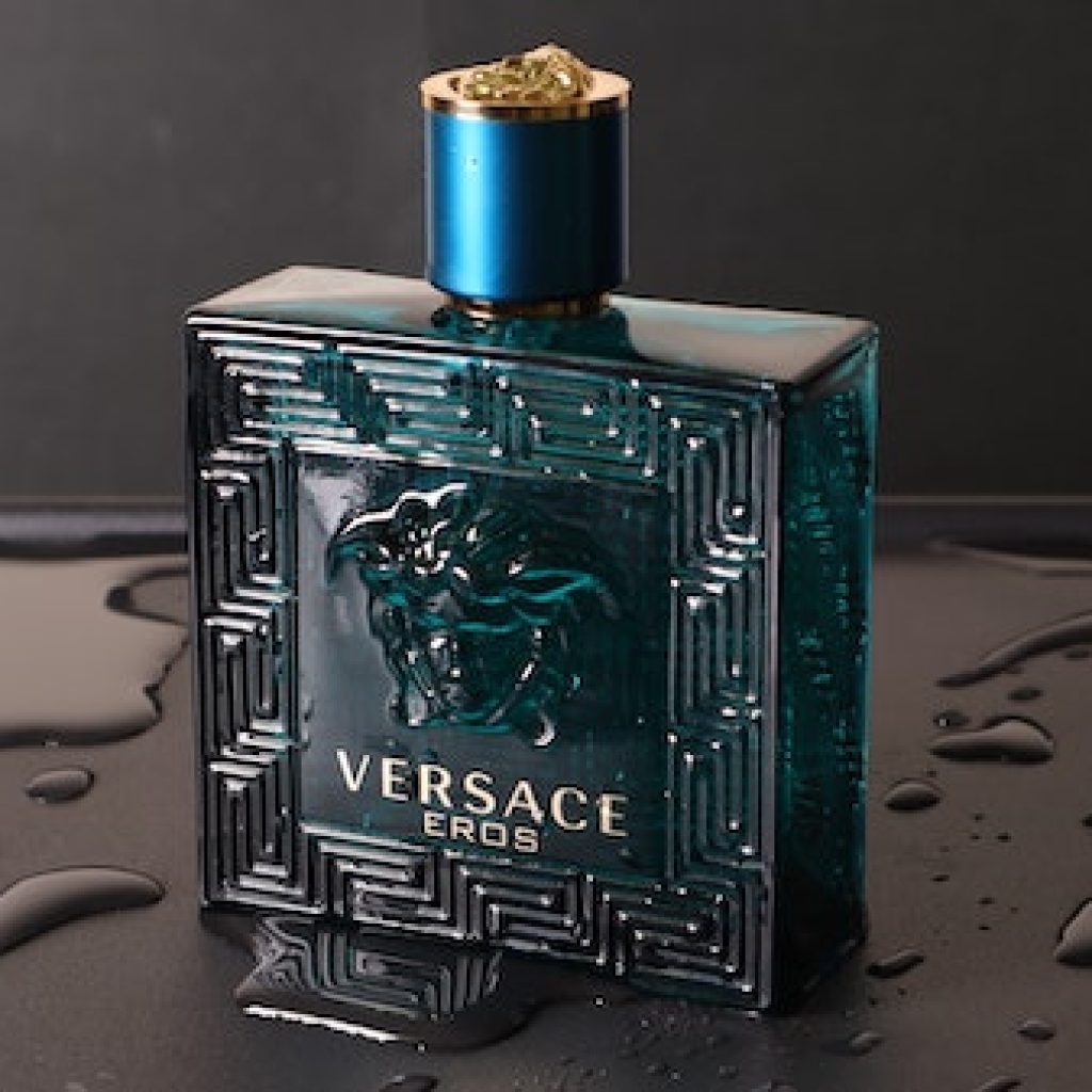 Versace cologne with key patterns on a wet, black table top