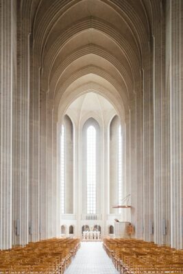 Facing straight to the center of a church with light wood seating making a path way