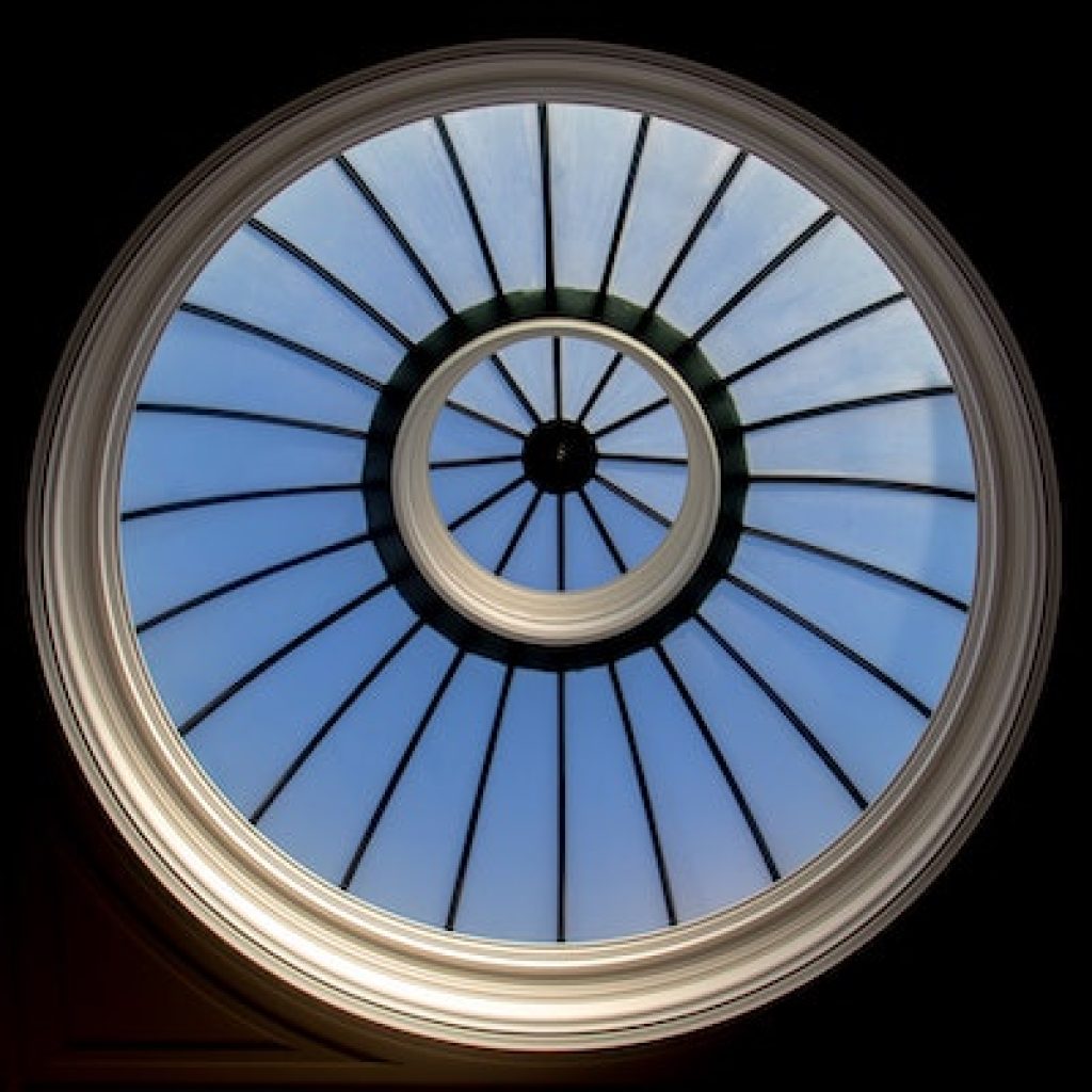 Round glass window in the ceiling with the view of the blue sky