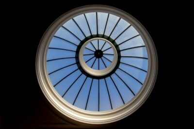 Round glass window in the ceiling with the view of the blue sky