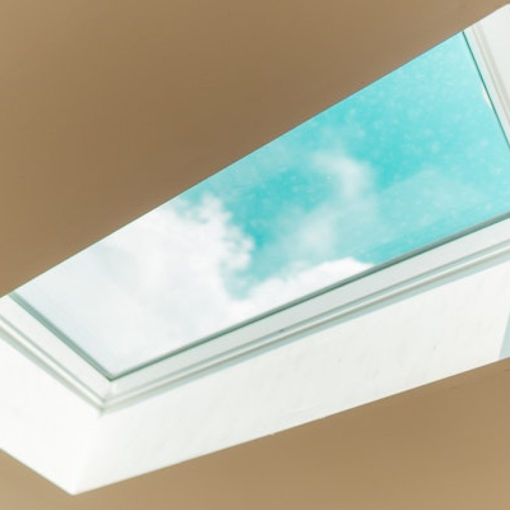 Skylight facing a cloud in the blue sky with white ceiling