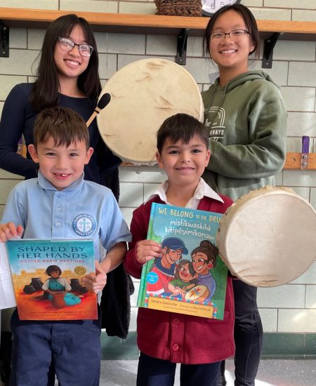 2 high school student educators with 2 young students holding books